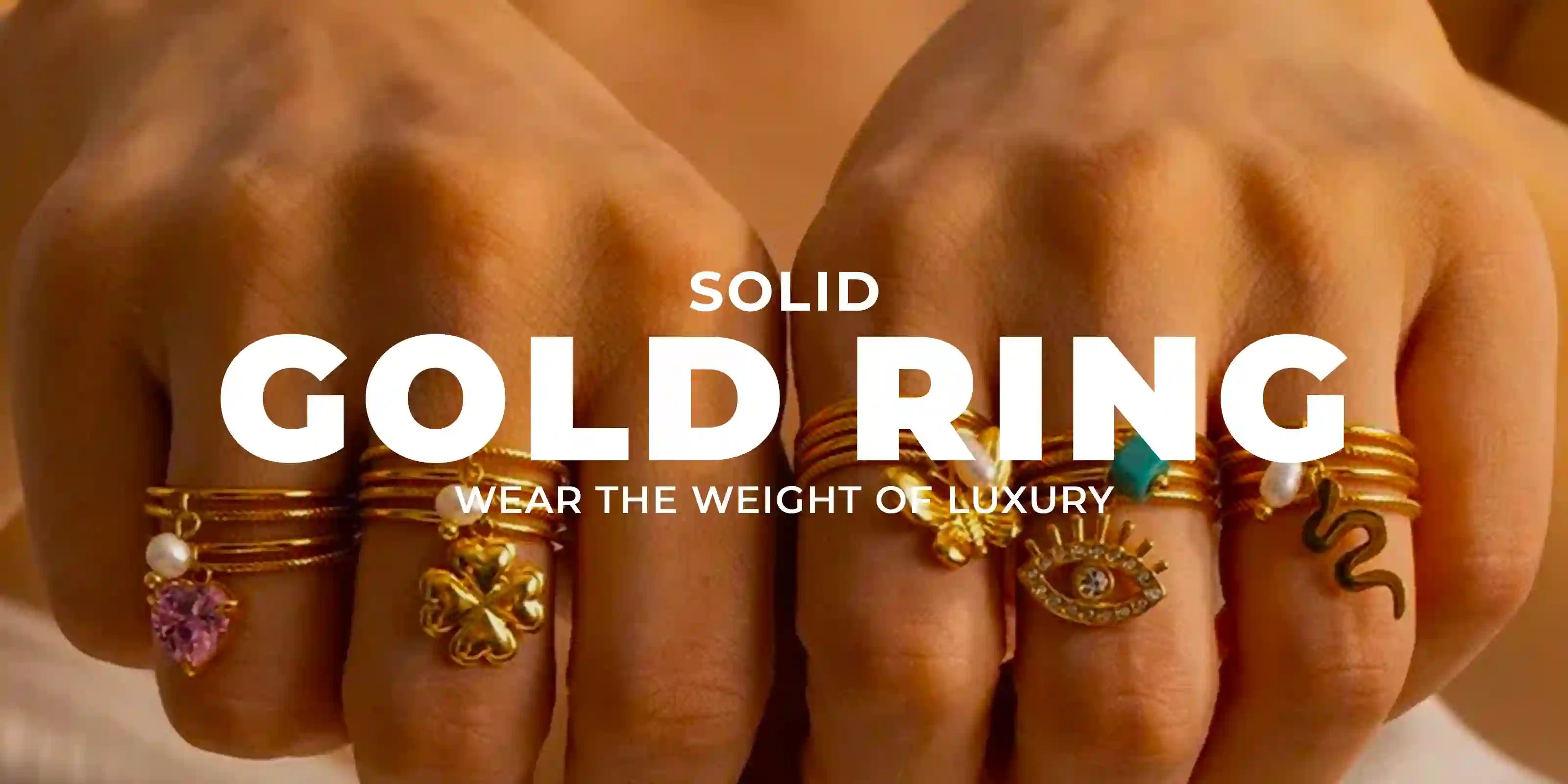 close-up of hands wearing multiple solid gold rings with charms like heart, clover, eye, and snake