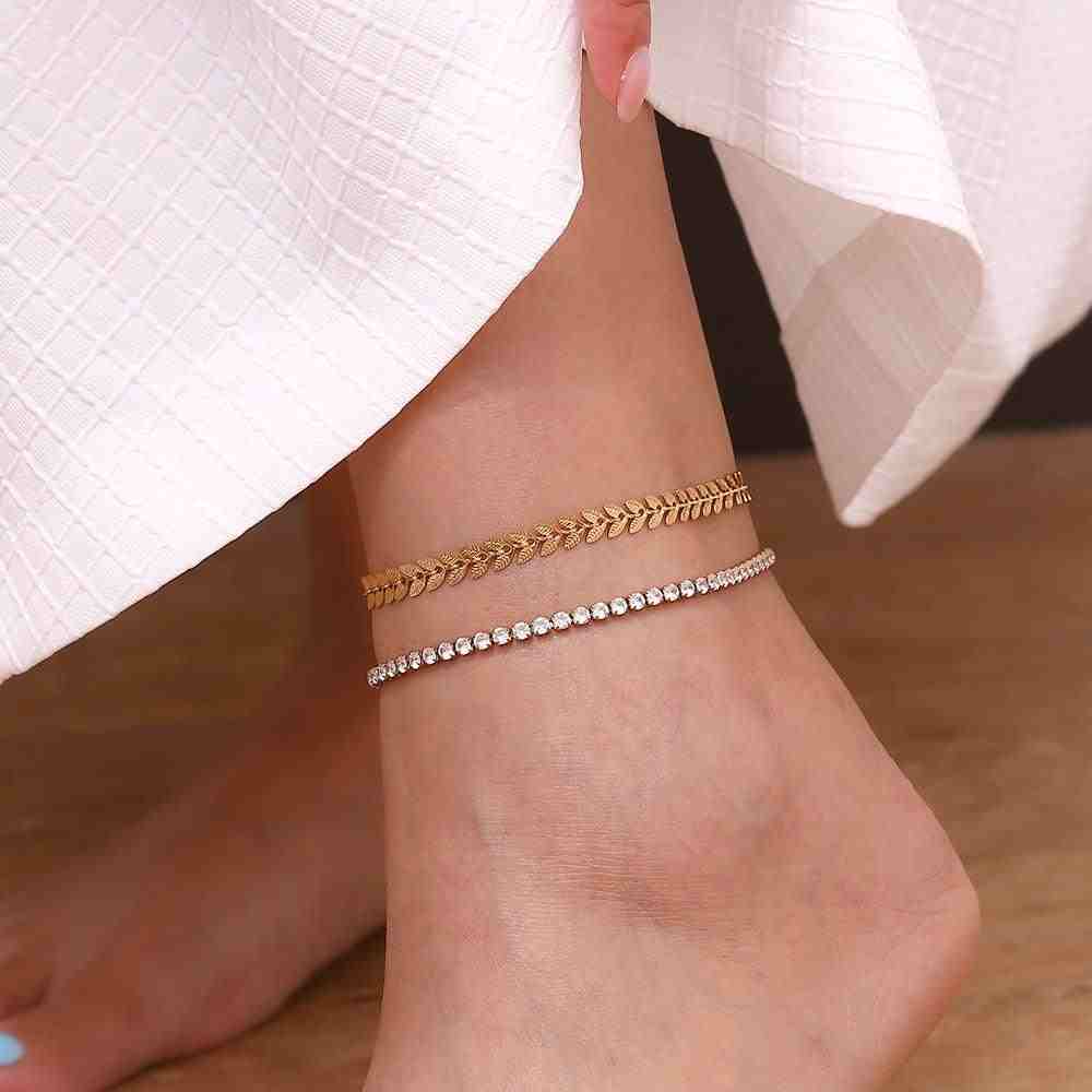 Wearing a gold plated leaf shaped chain anklet with another anklet beaded design white pearl stones.