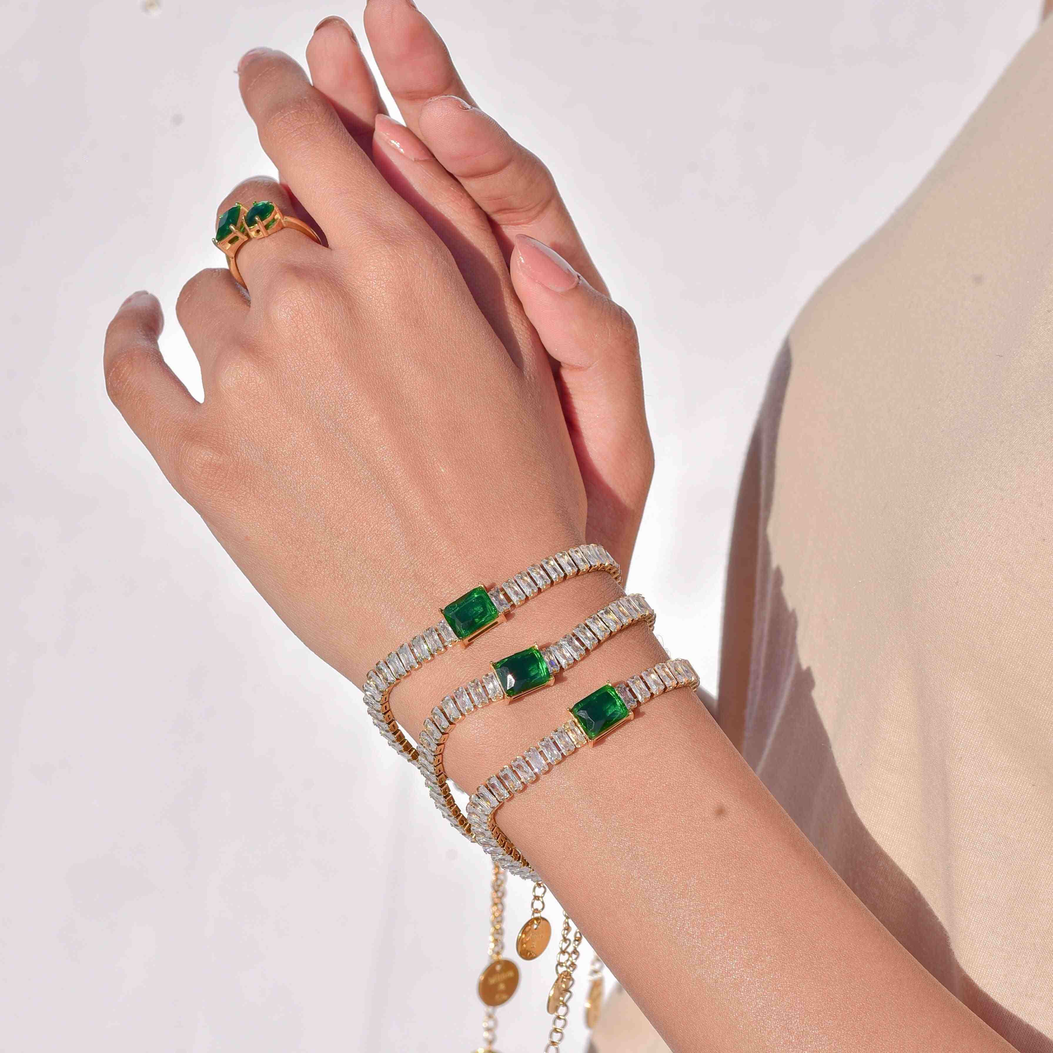 18k Gold plated emerald bracelet stack in left hand. Buy Online at Mithra and Co.