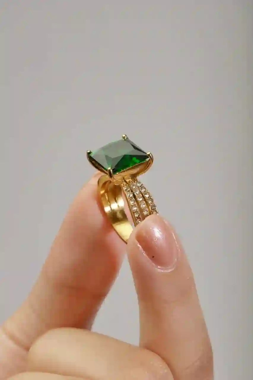 holding Aura Ring Gold Square Engagement Ring. Classic Green stone and shine.