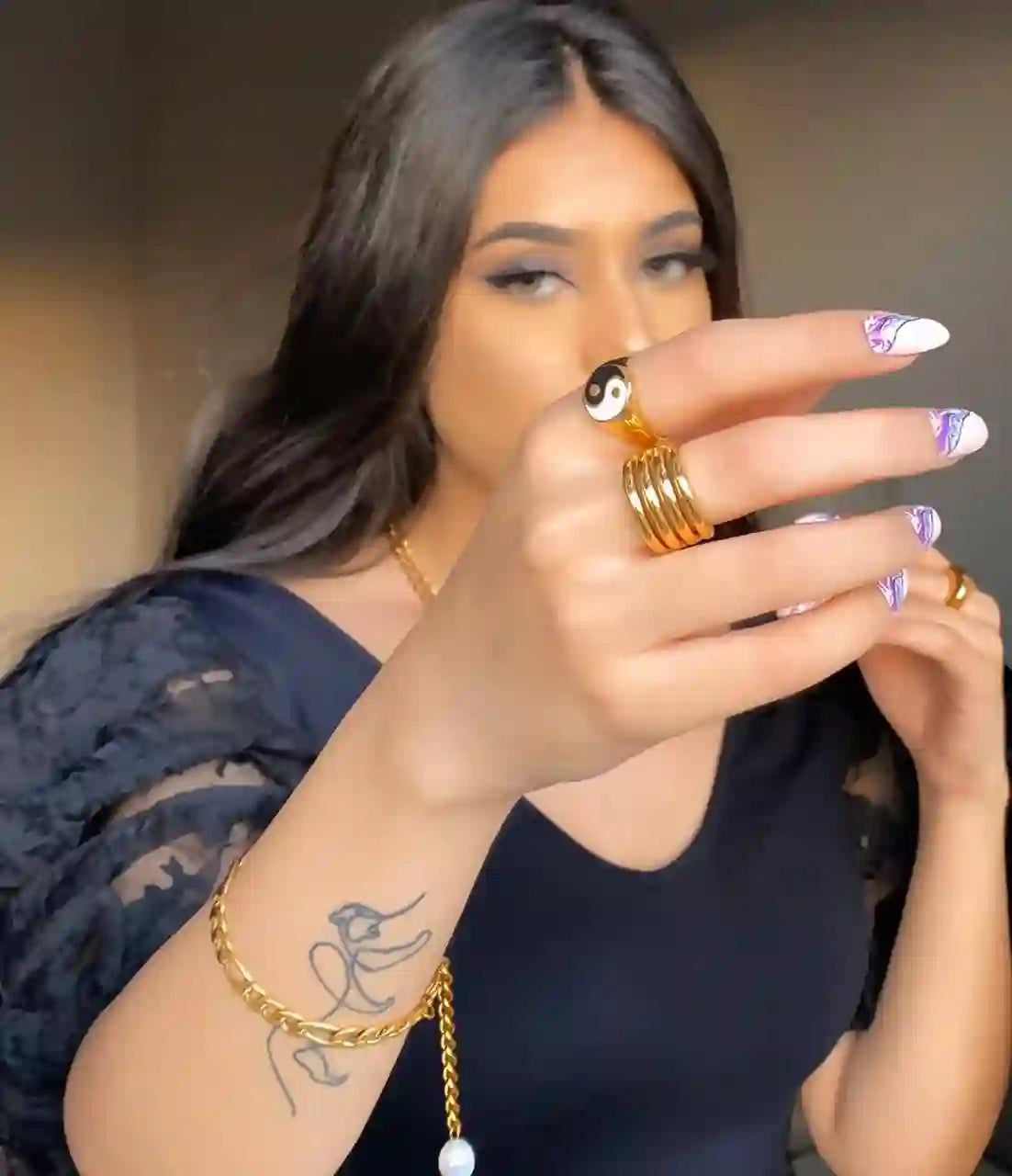 Woman wearing 18k Gold Plated Yin Yang ring and multiple gold rings with gold bracelet