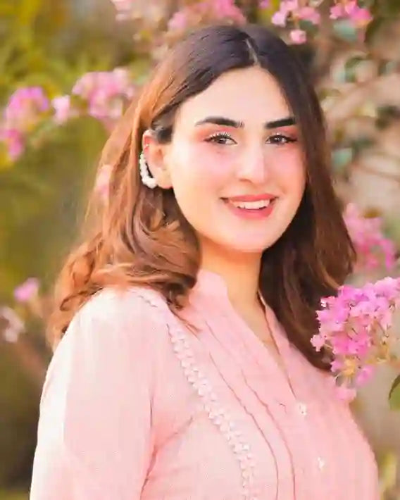woman wearing 18k Gold Plated earrings smiling outdoors near pink flowers in soft natural light
