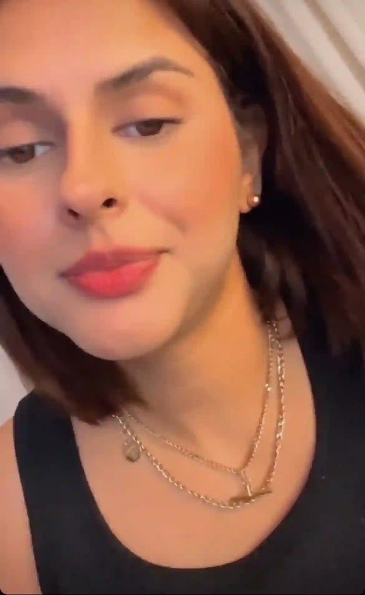 Woman wearing 18k Gold Plated layered necklaces and gold earrings with a black top