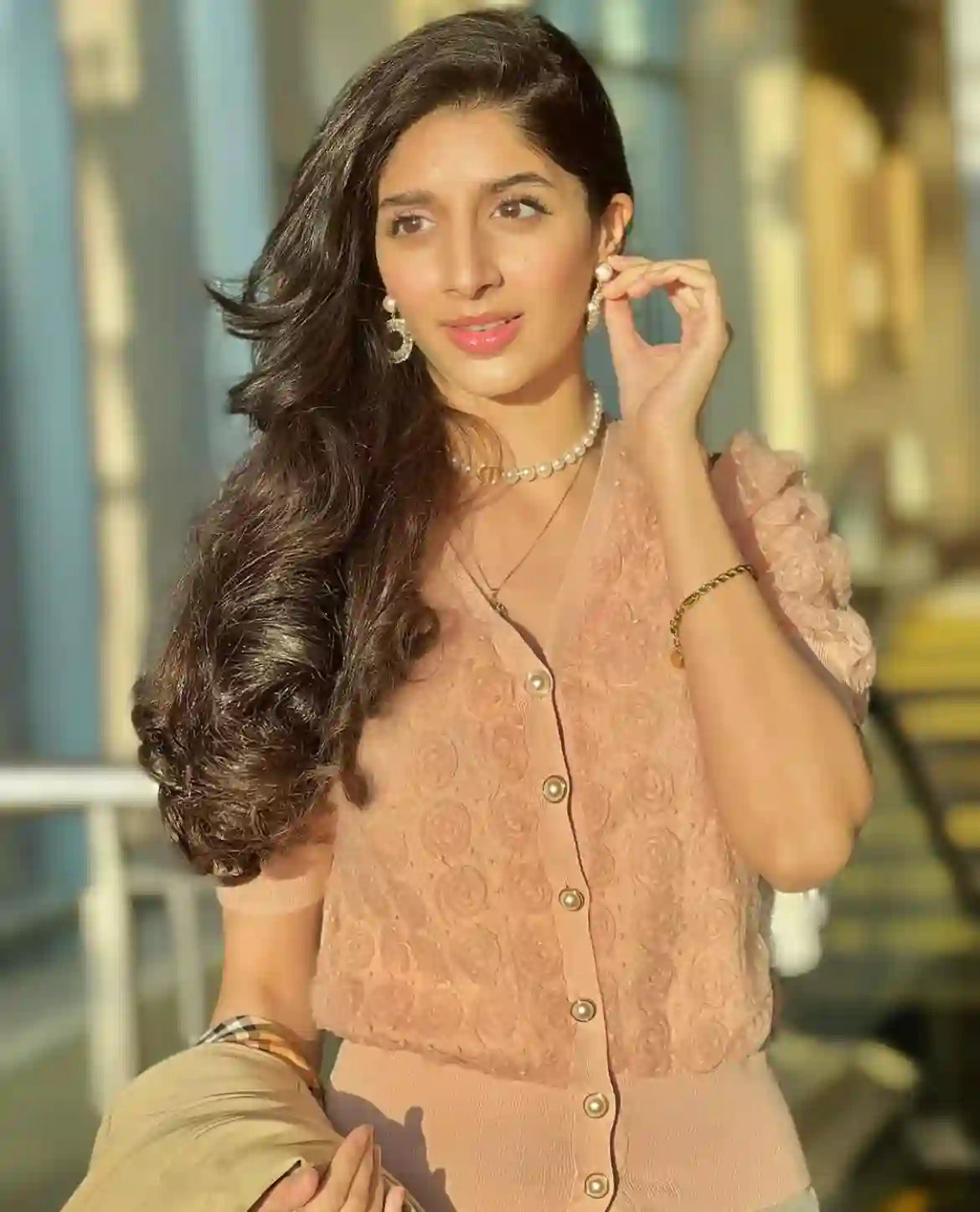 Woman wearing 18k Gold Plated pearl jewelry including necklace and earrings with peach blouse in sunlight