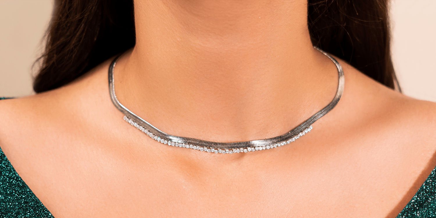 Silver necklace on a person with a neutral background