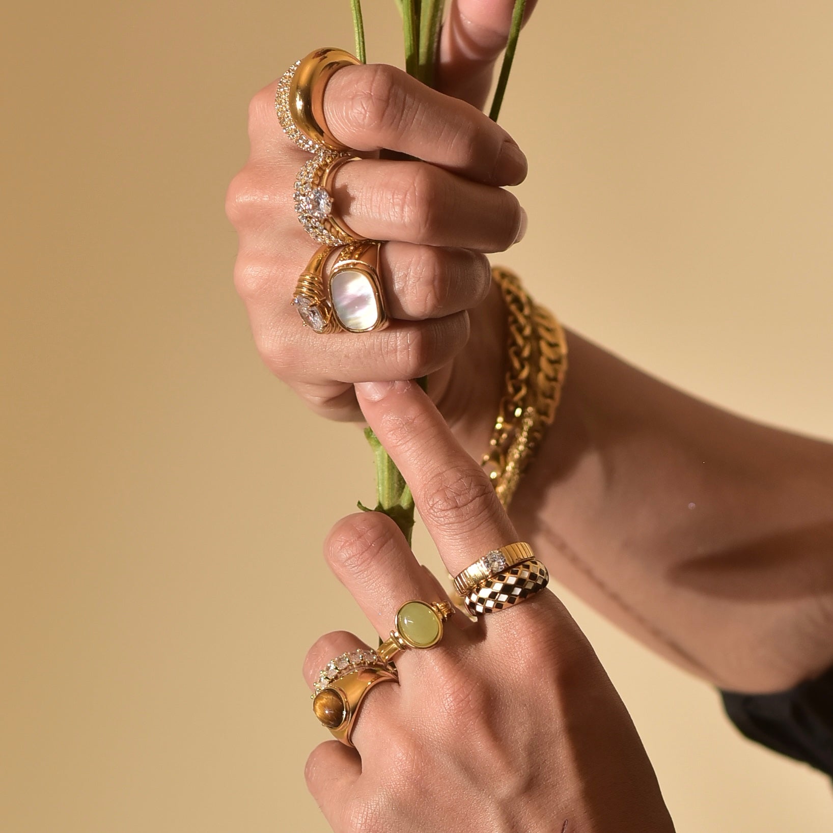 woman wearing 18k Gold Plated rings with gemstones and crystals, holding a flower stem